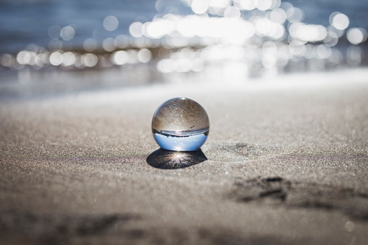 A photo of a transparent glass ball on a beach